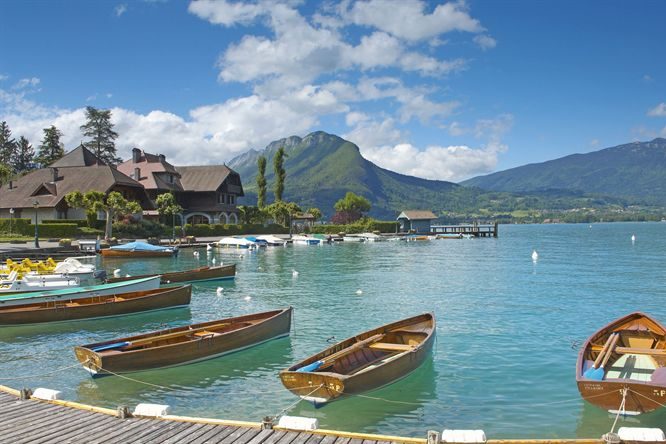 Paysage alpin verdoyant avec un village pittoresque et des montagnes en arrière-plan.
