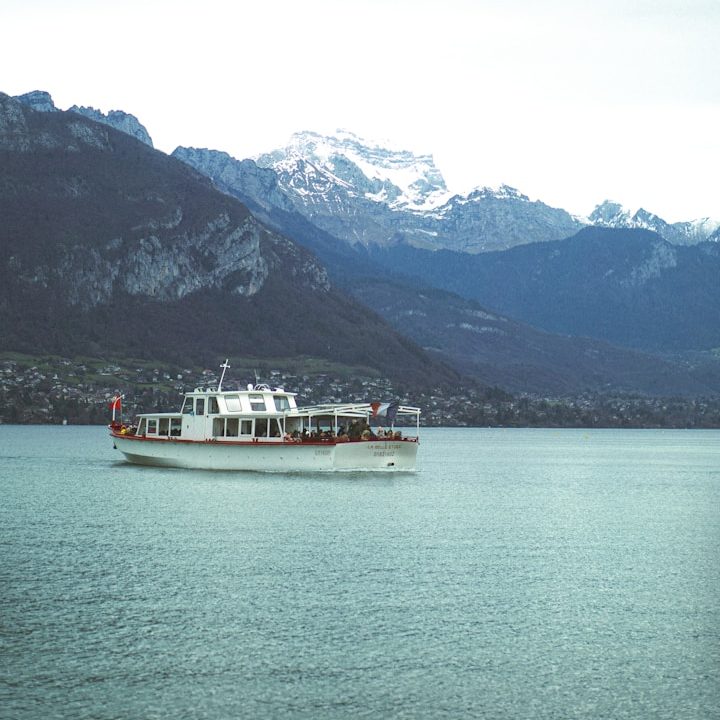 Bateau de croisière sur un lac, avec montagnes en arrière-plan.