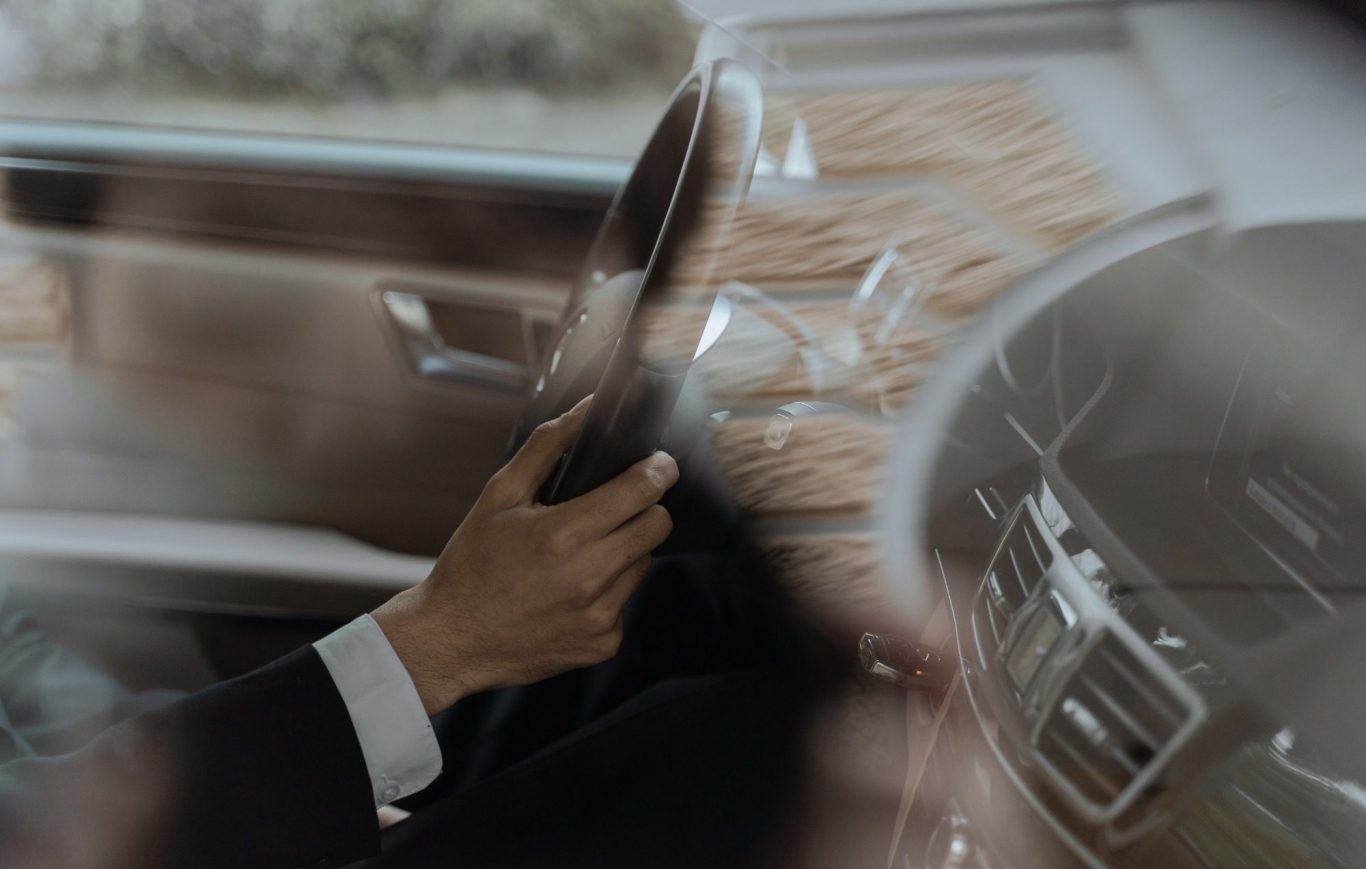 Classe-Affaires VTC - Chamonix - Chauffeur Privé A driver's hand holding the steering wheel, seen through the blurred windshield.