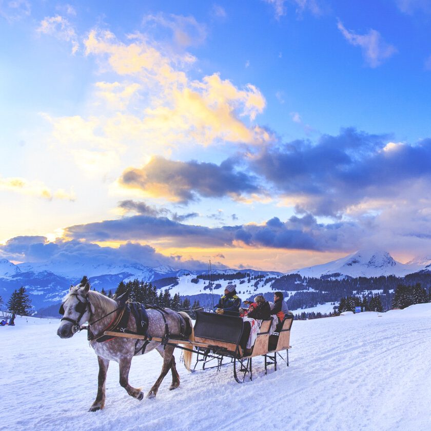 Classe-Affaires VTC Chamonix Mont-Blanc Morzine Avoriaz Traîneau tiré par des chevaux sur la neige à Avoriaz, avec un ciel coloré au coucher du soleil.