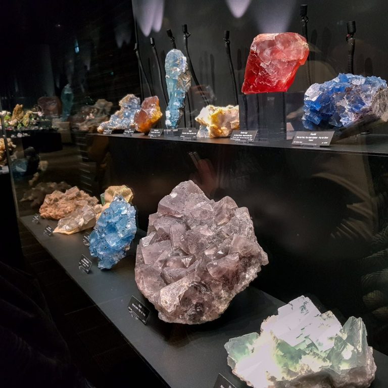 Vitrine de minéraux colorés, incluant quartz, améthyste et topaze.