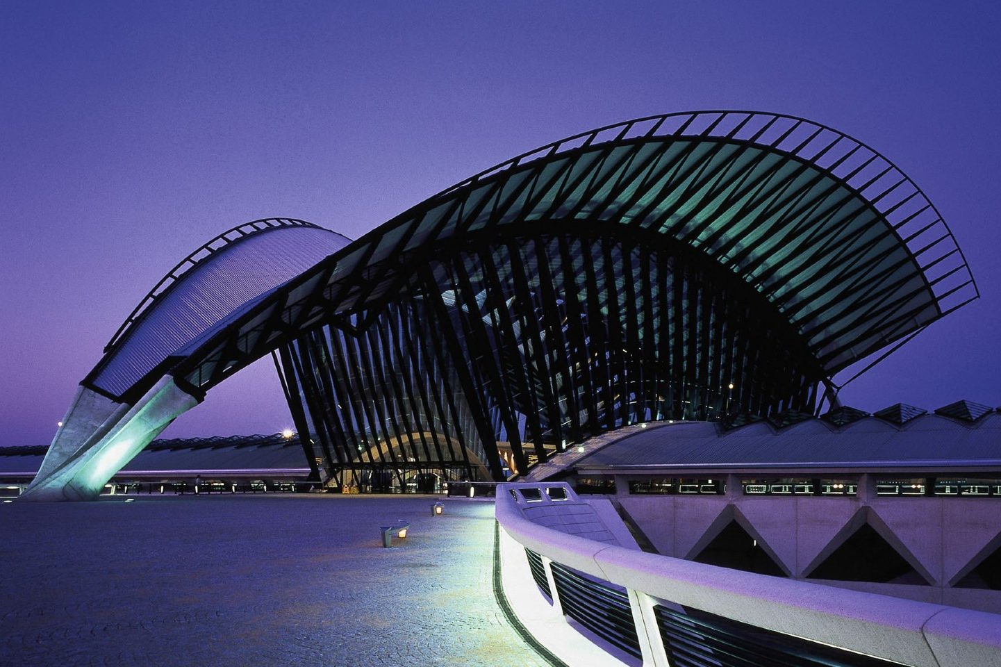 Architecture moderne avec une structure ondulée, éclairée par une lumière violette.