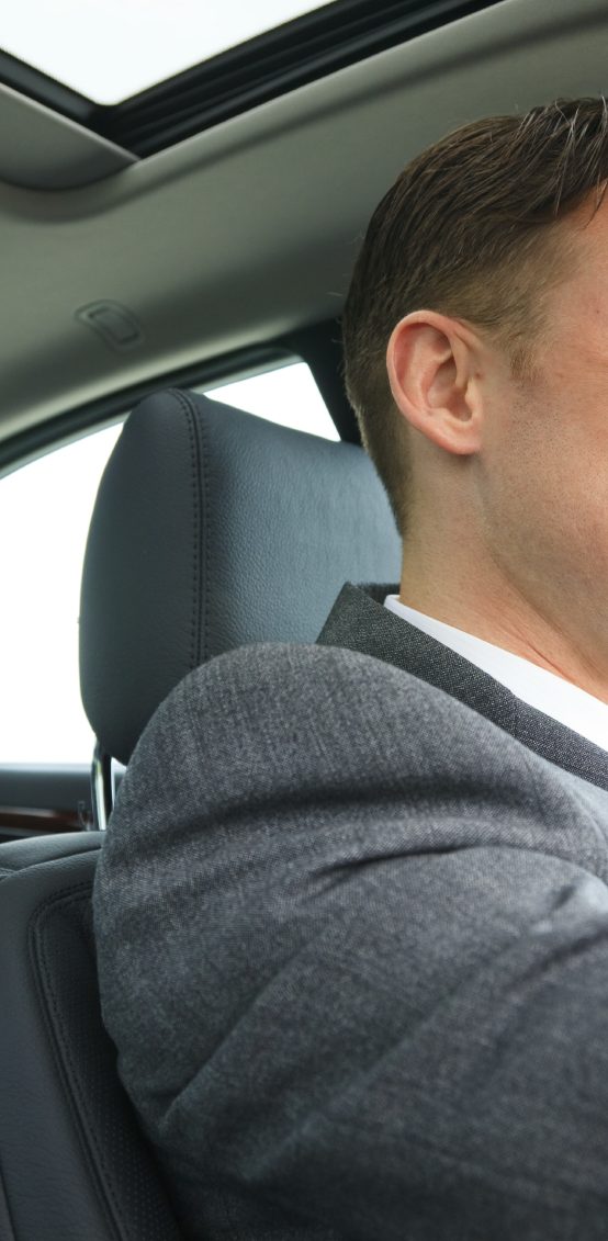 VTC Taxi Classe-Affaires VTC en Haute-Savoie Homme en costume au volant d'une voiture, vue de profil.